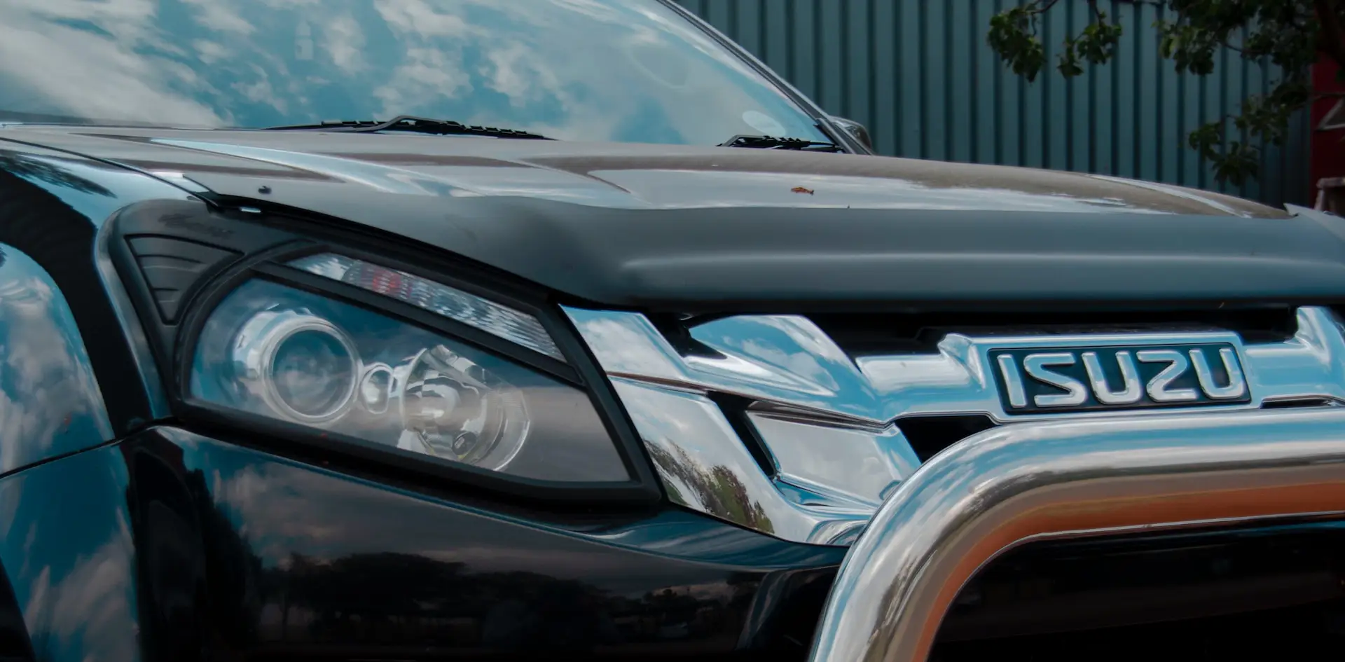 close up of an isuzu car logo, headlight and front bumper