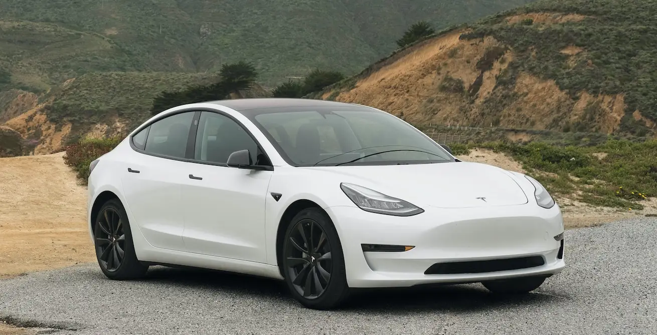 white tesla car parked on a concreted hillside in front of mountains